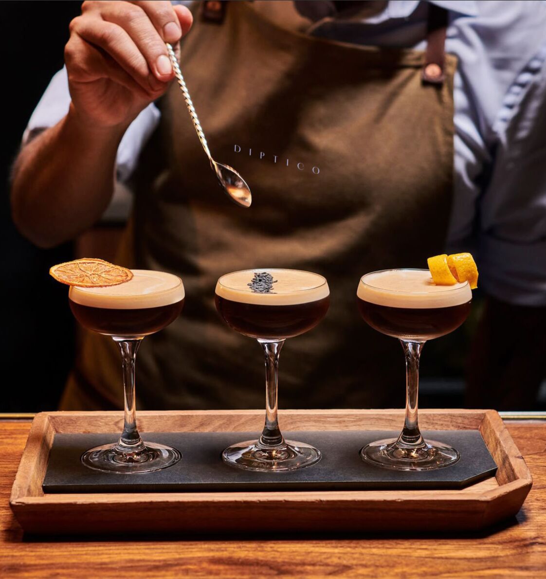 Bartender garnishing three cocktails on a Diptico tray