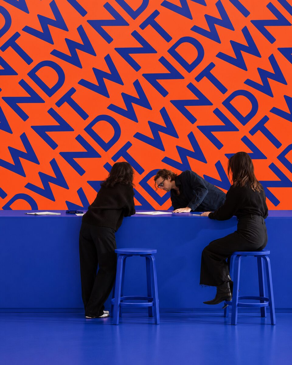 Blue DWNTWN registration desk against an orange lettering wall